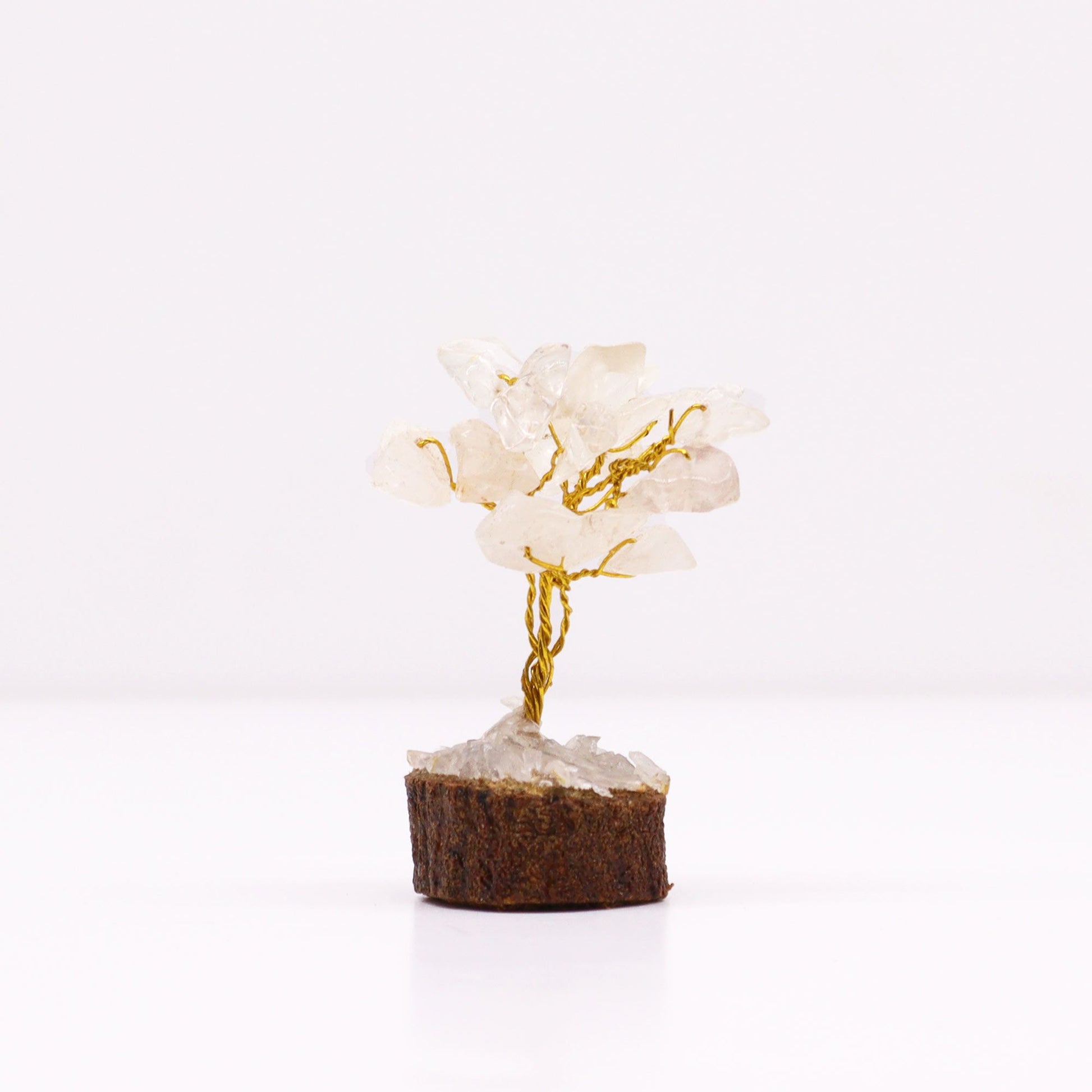 Miniature gemstone tree with clear rock quartz crystal chips on wire branches, mounted on a natural round wooden base.