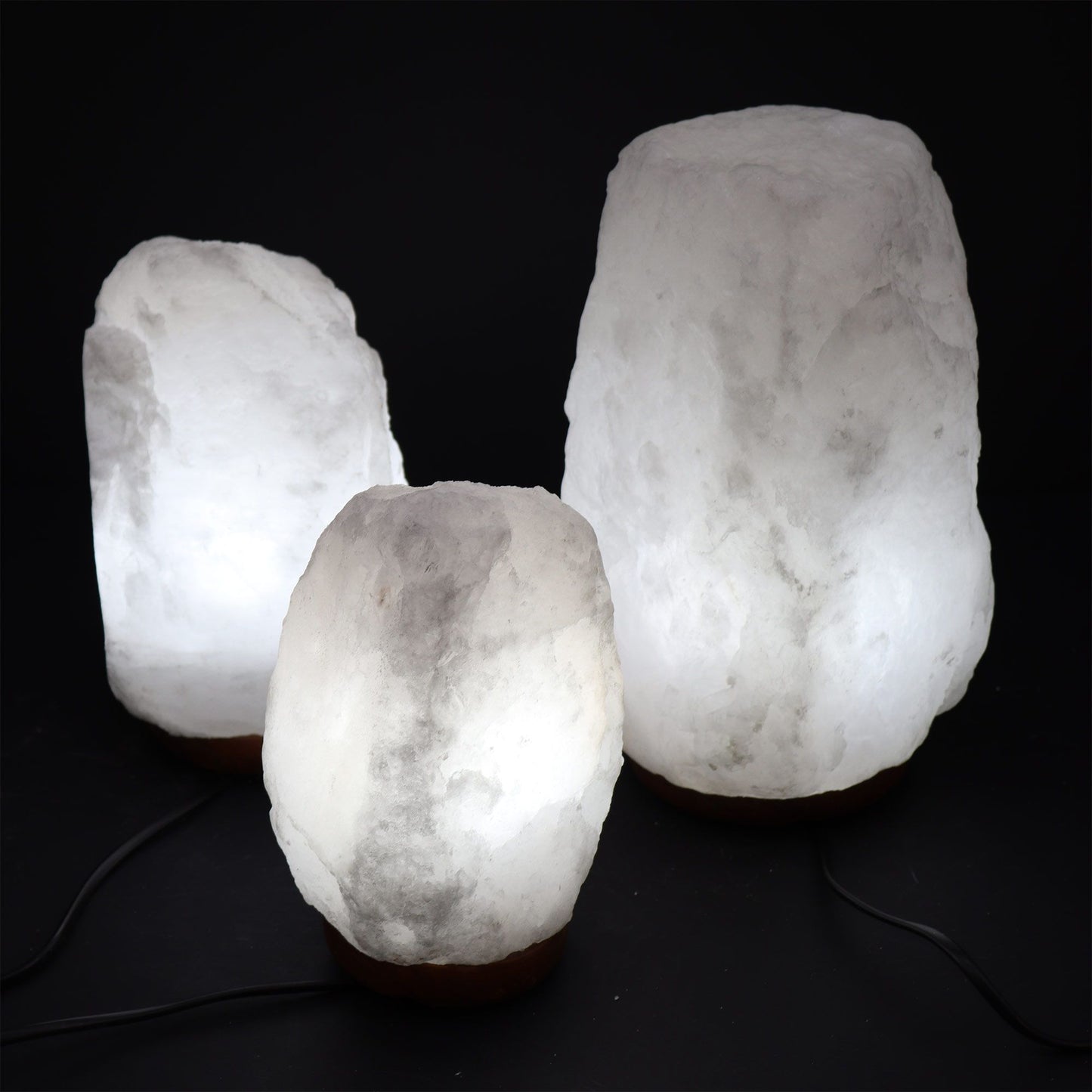 Natural pink Himalayan salt lamp carved into a rough rock shape on a wooden base, emitting a warm orange glow.