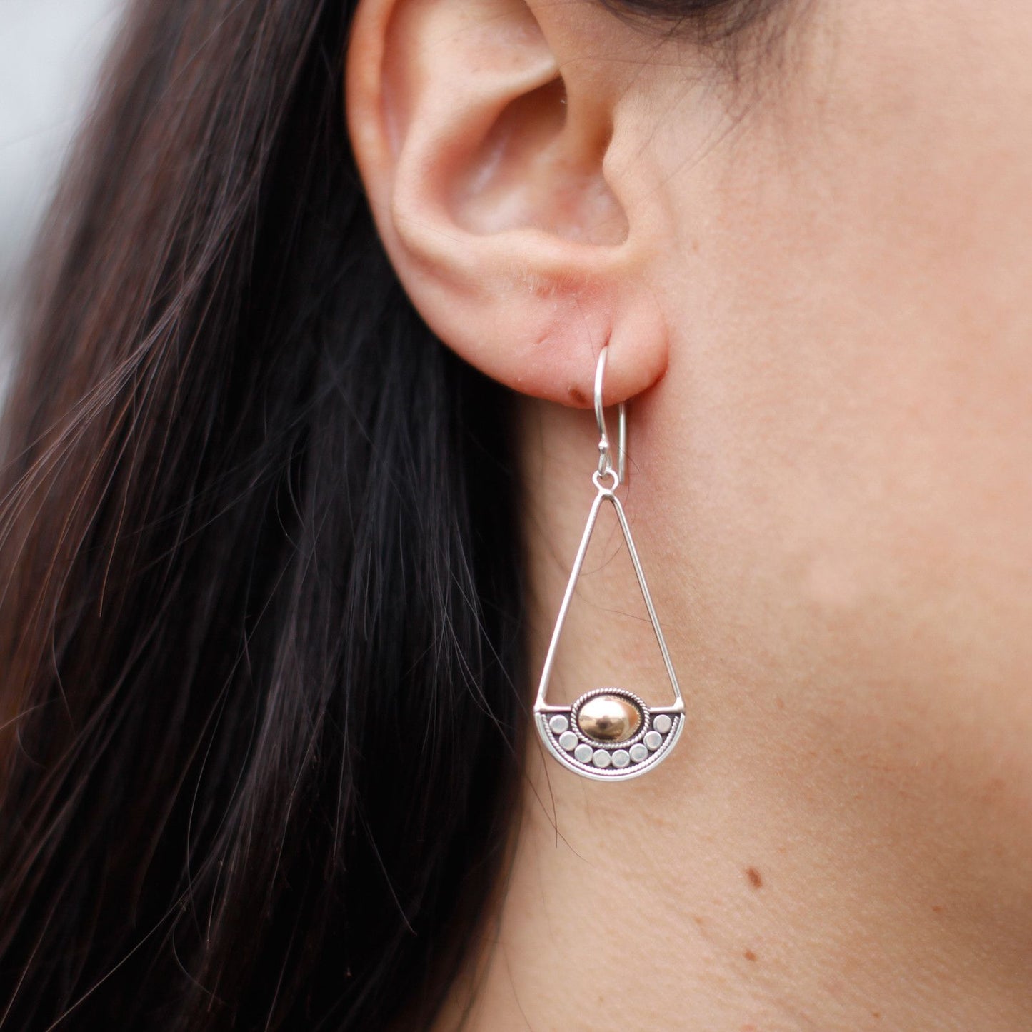 Elegant mixed metal earrings featuring a combination of silver and gold finishes with a mystical design.