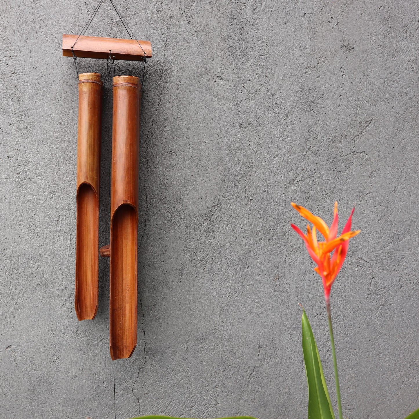 Large natural finish bamboo windchime with four thick hollow tubes hanging from a wooden canopy.