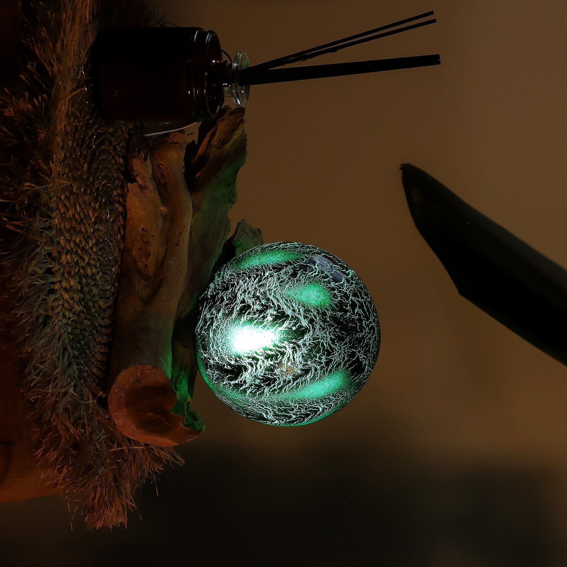 Atmospheric table lamp with a dark emerald crackle glass sphere resting on a natural Indonesian driftwood base.