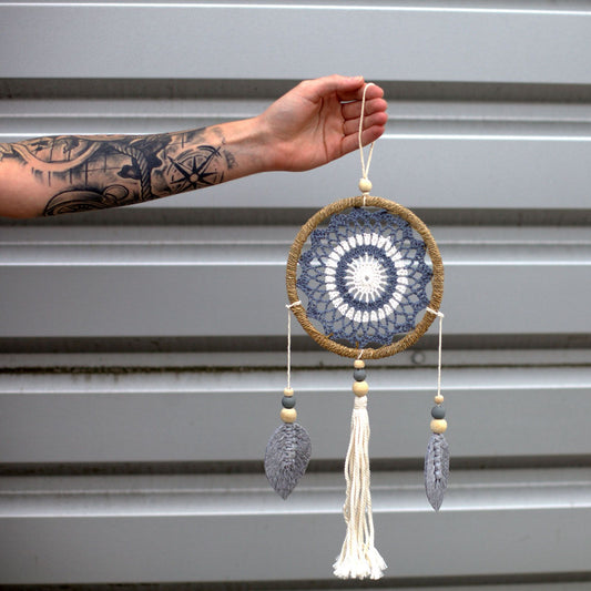 Handmade medium grey dream catcher with a woven web and natural fabric hangings, featuring a feather-free vegan design.