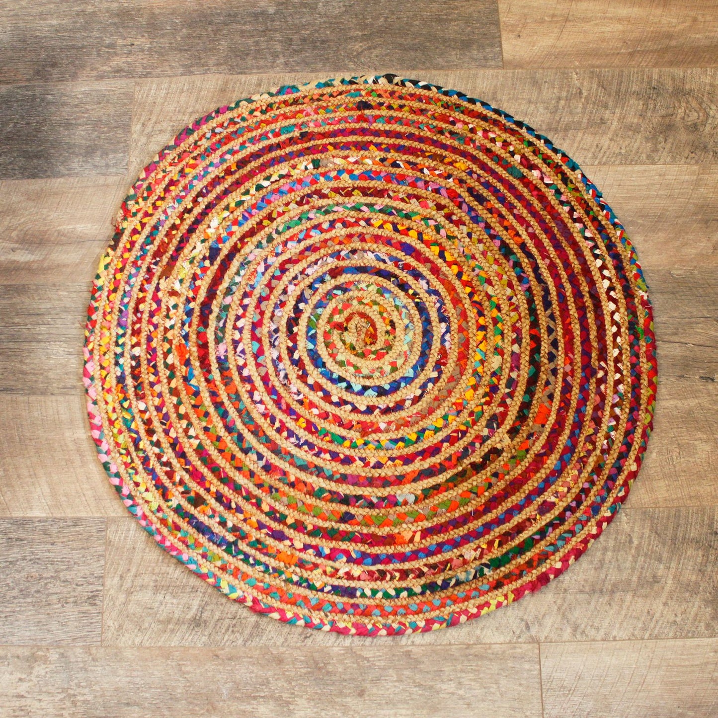 Handmade round rug crafted from natural jute and colourful recycled cotton sari fabric in a circular braided pattern.