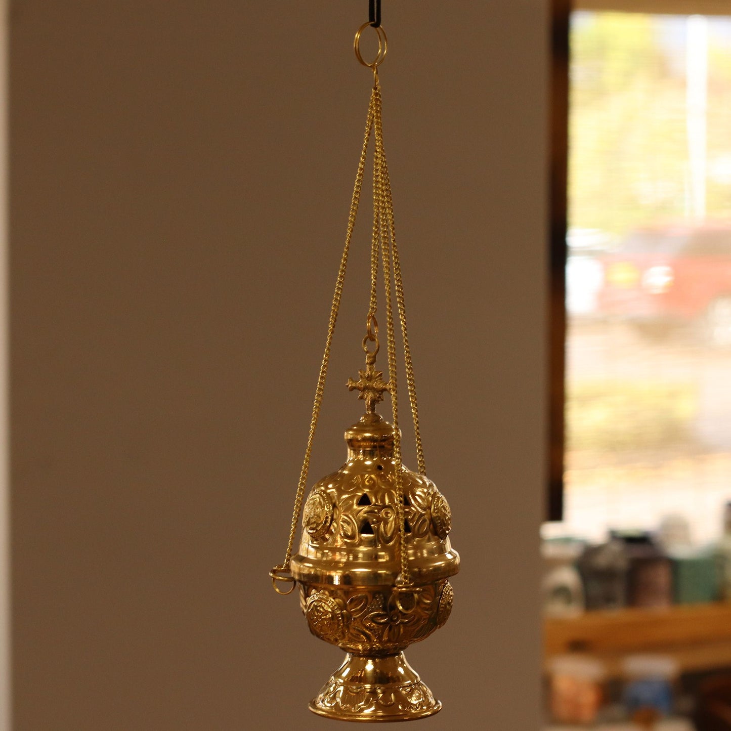 Intricate hanging brass incense burner with detailed engravings, a cross finial, and a long suspension chain.