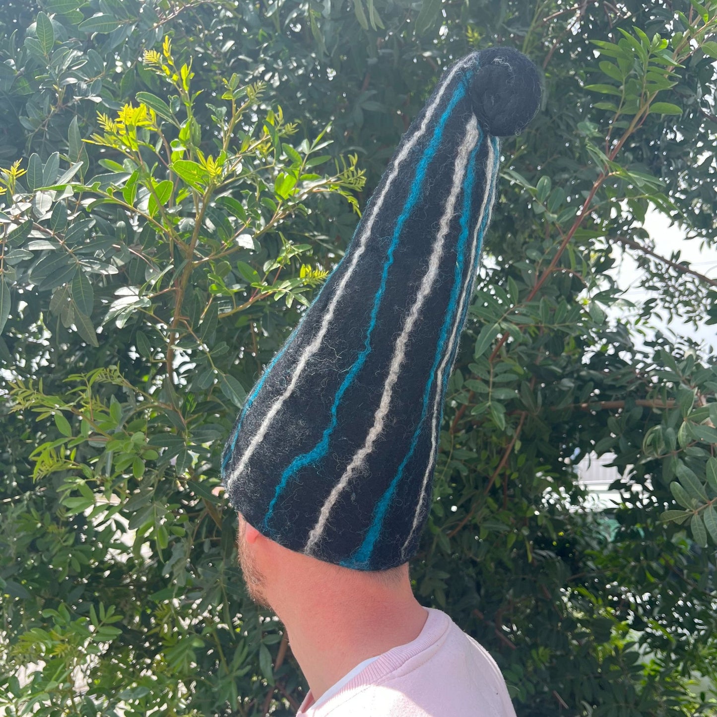 Pointed felted sauna hat in black with striking blue streaks, designed in a whimsical wizard style.