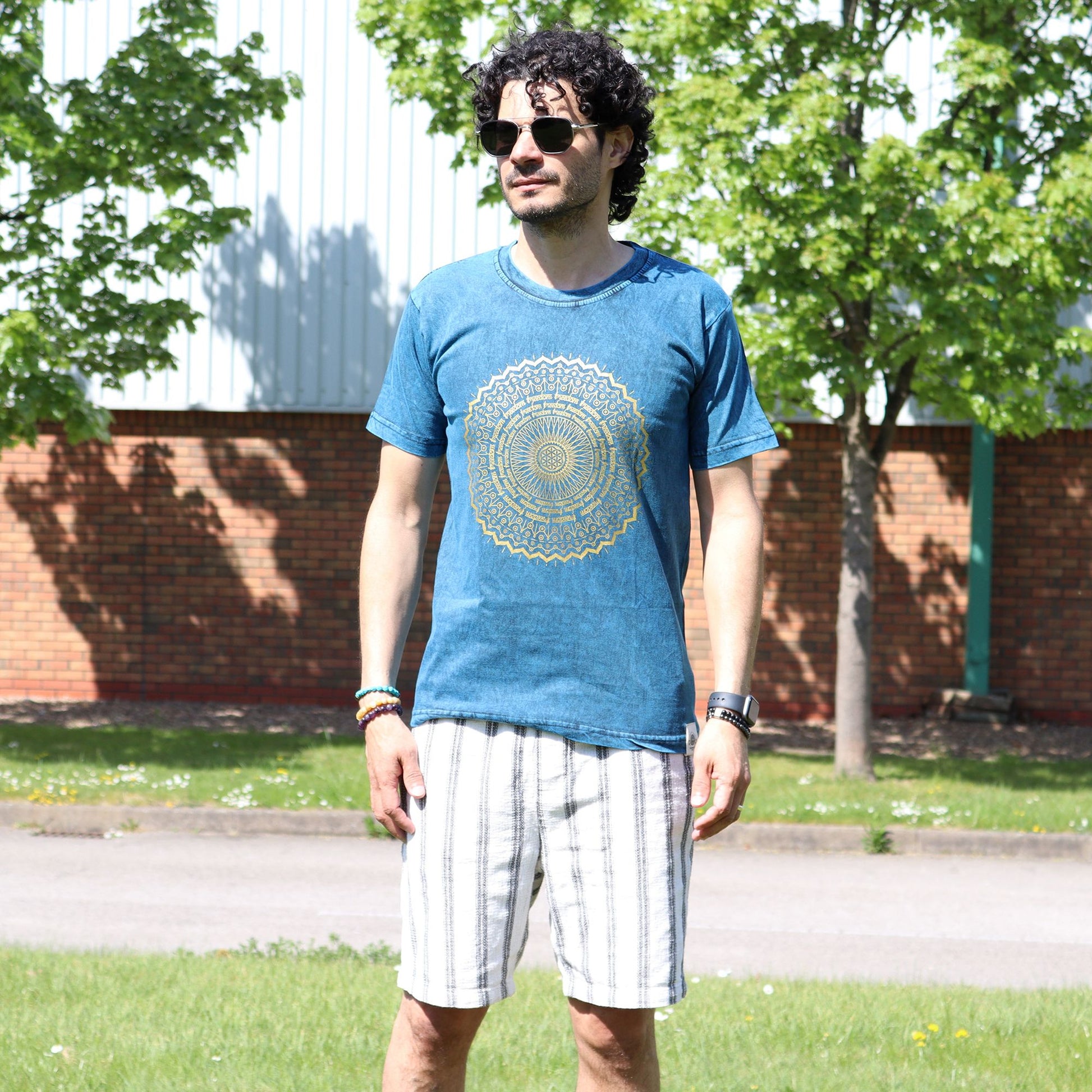 Close-up of a blue stonewashed cotton t-shirt featuring an intricate white mandala print on the front.