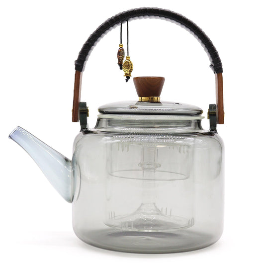 Large clear glass teapot with a sleek charcoal grey infuser and steamer system showing tea leaves steeping inside.