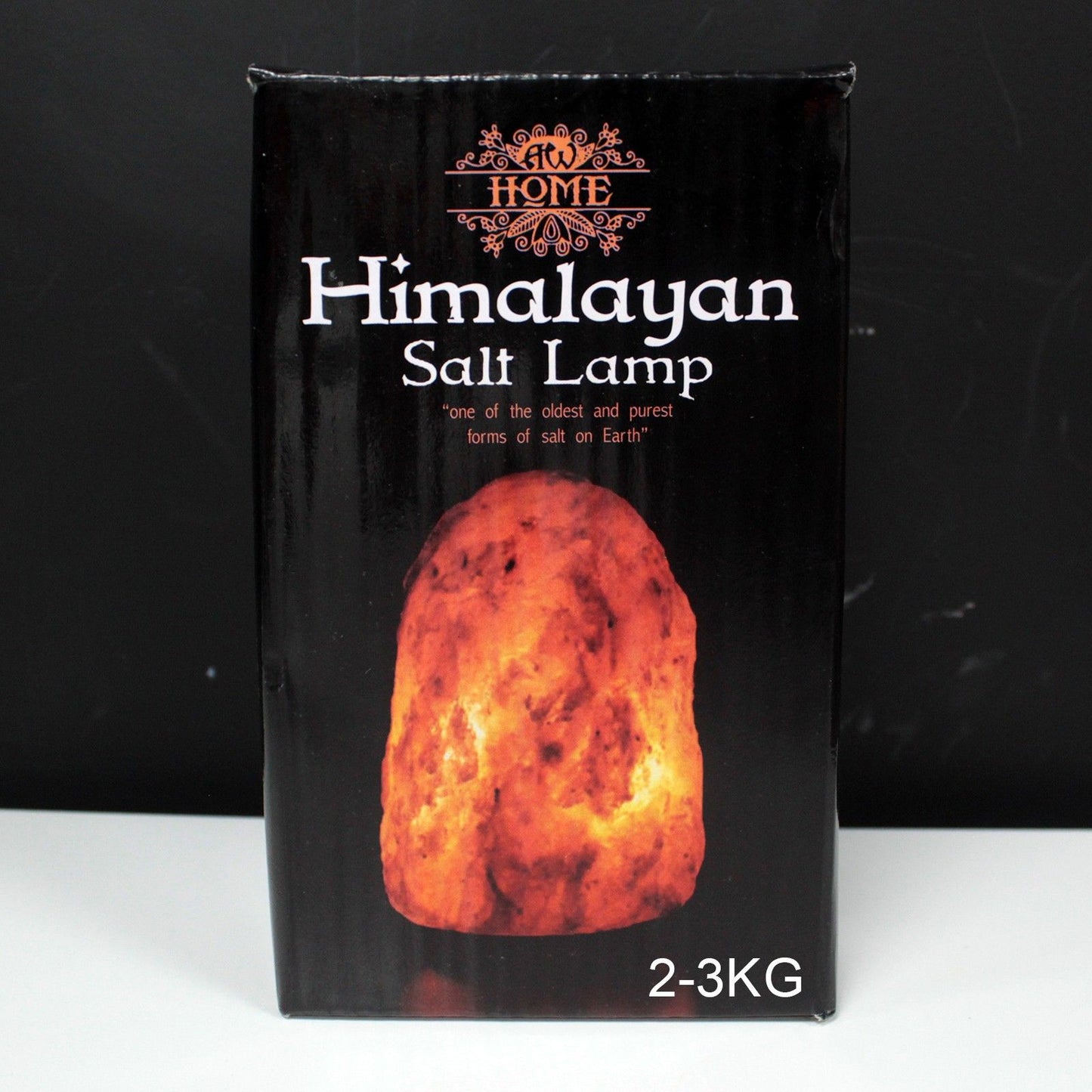 Hand-carved natural pink Himalayan salt lamp on a wooden base emitting a warm orange glow.