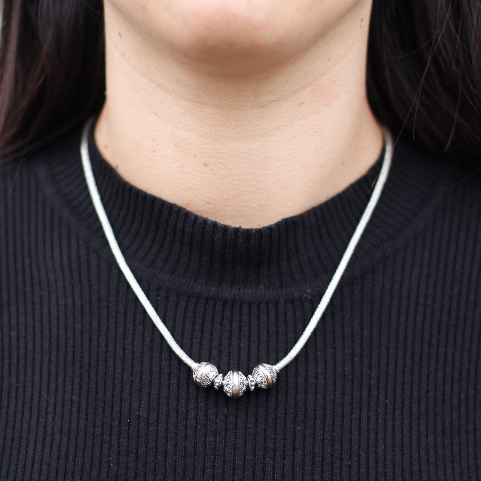 Elegant mixed metal necklace featuring a delicate triangle pendant in contrasting silver and gold finishes.