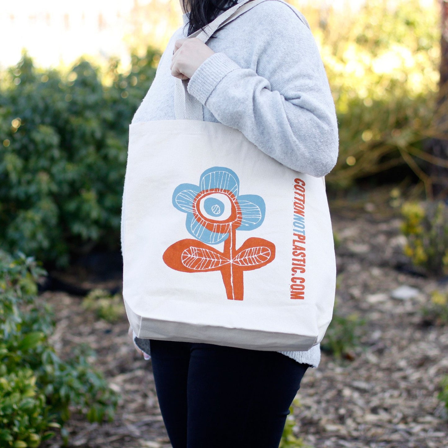 Large eco-friendly cotton tote bag featuring a vibrant bright flower design and sturdy shoulder handles.