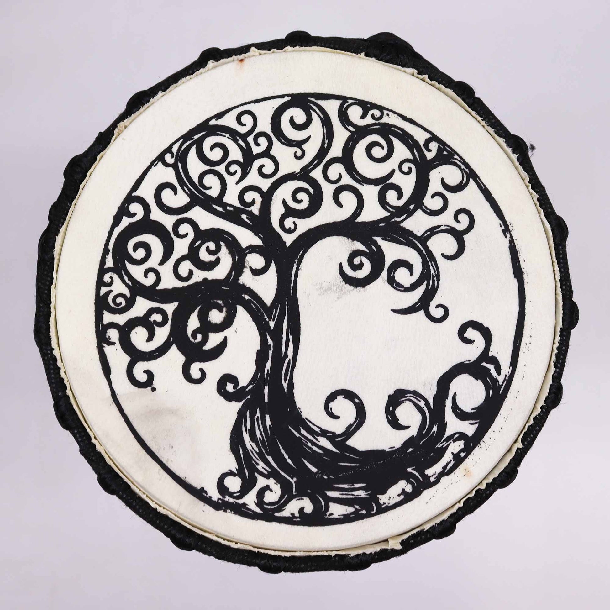 Handcrafted wooden djembe drum with a wide top and an intricate Tree of Life design on the natural drum skin.