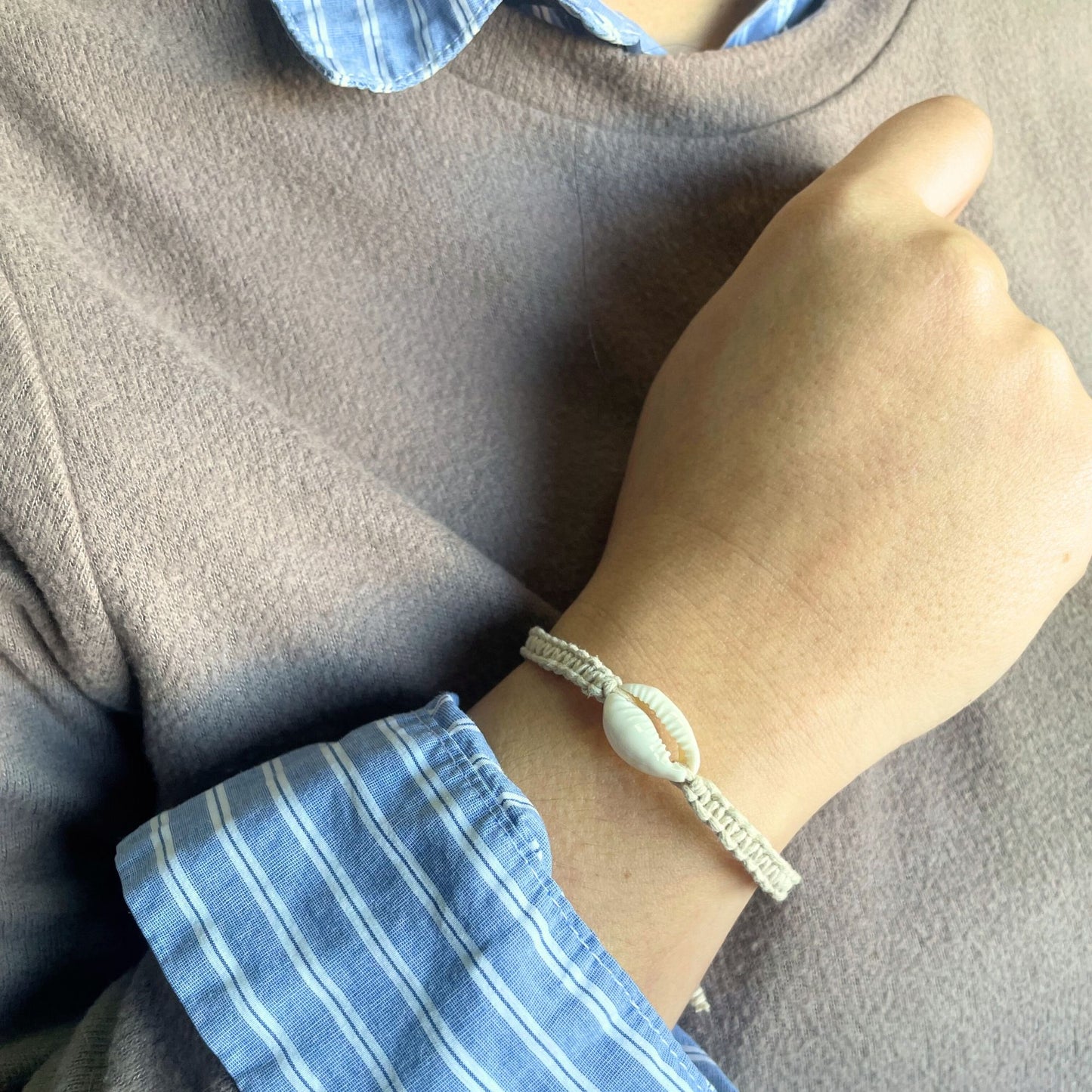Handmade woven friendship bracelet featuring small white cowrie shells on a colourful cord.