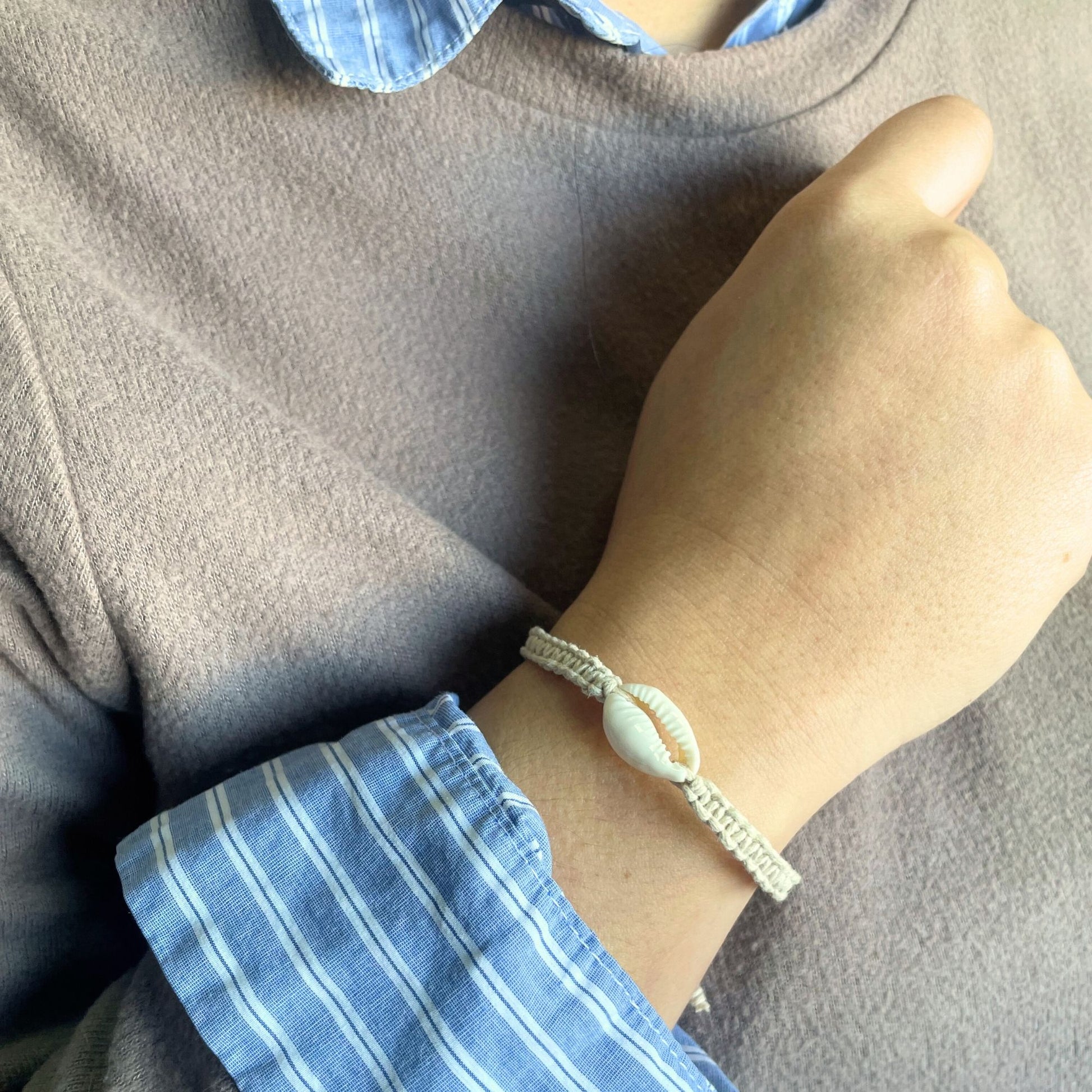 Handmade woven friendship bracelet featuring small white cowrie shells on a colourful cord.
