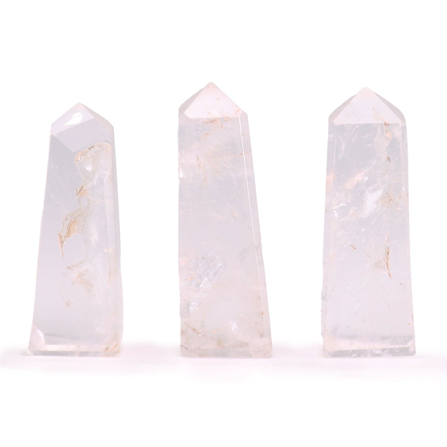 A small, polished Clear Quartz gemstone obelisk with a pointed top and smooth, transparent facets.