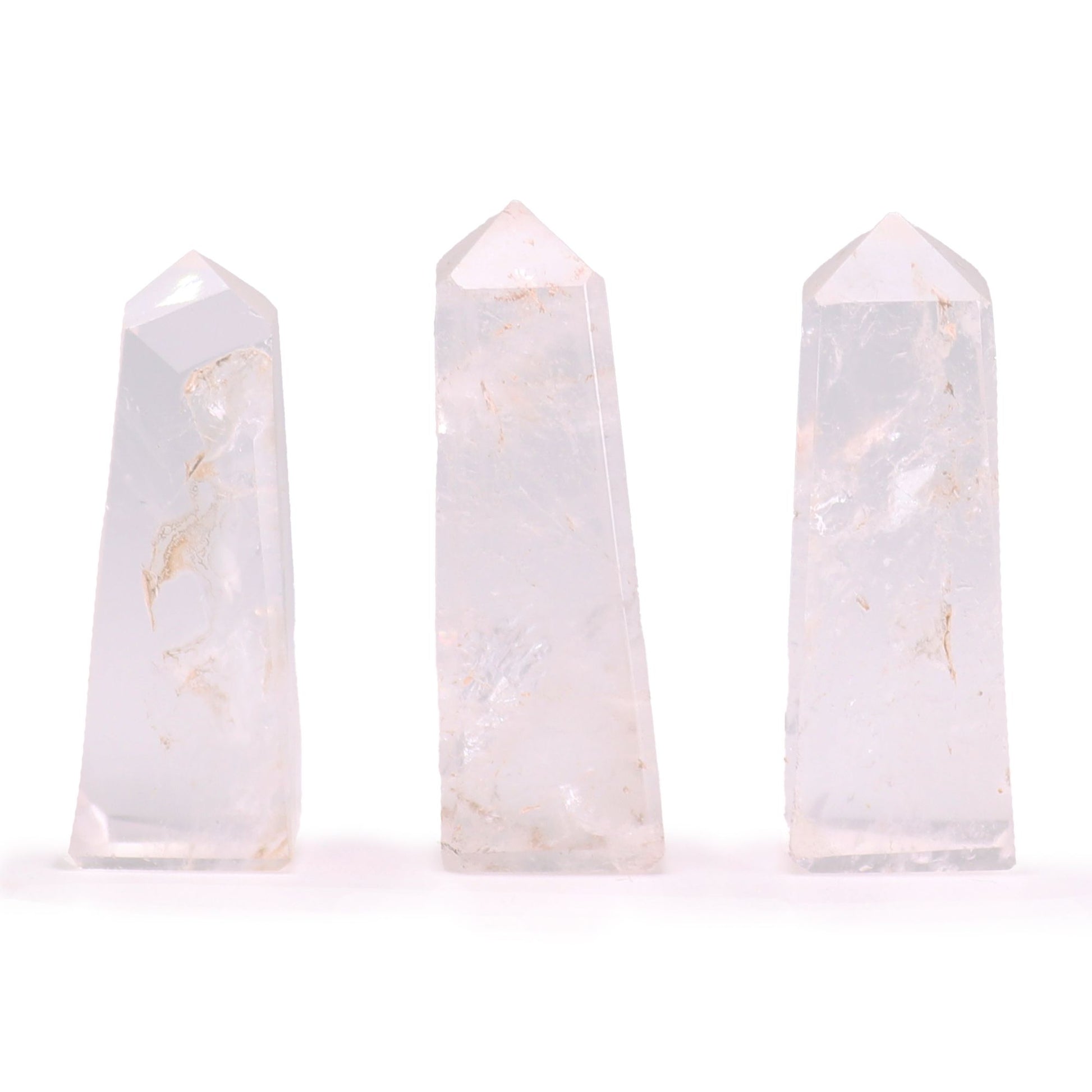 A small, polished Clear Quartz gemstone obelisk with a pointed top and smooth, transparent facets.
