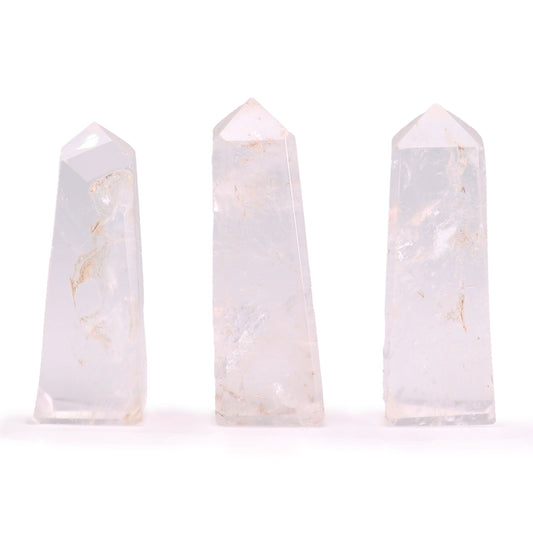 A small, polished Clear Quartz gemstone obelisk with a pointed top and smooth, transparent facets.