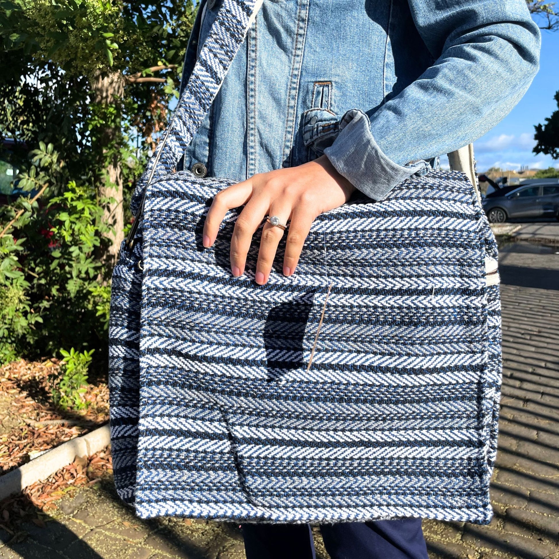 Soft fabric laptop bag featuring a vibrant blue and white striped pattern with a secure zip closure.