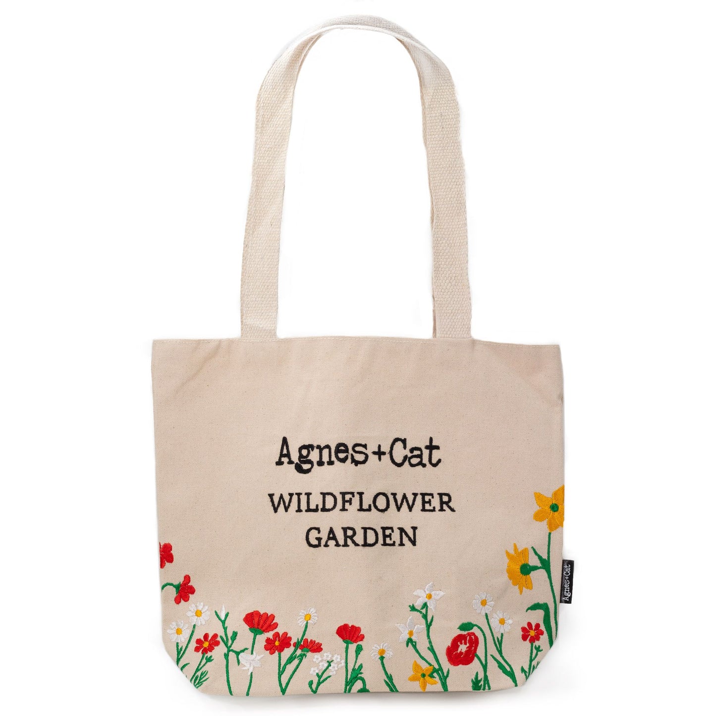 Cream cotton tote bag with delicate embroidered red wildflowers and green leaves in a meadow-inspired design.