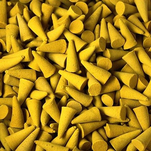 Large pile of yellow citronella incense cones with a textured surface on a neutral background.