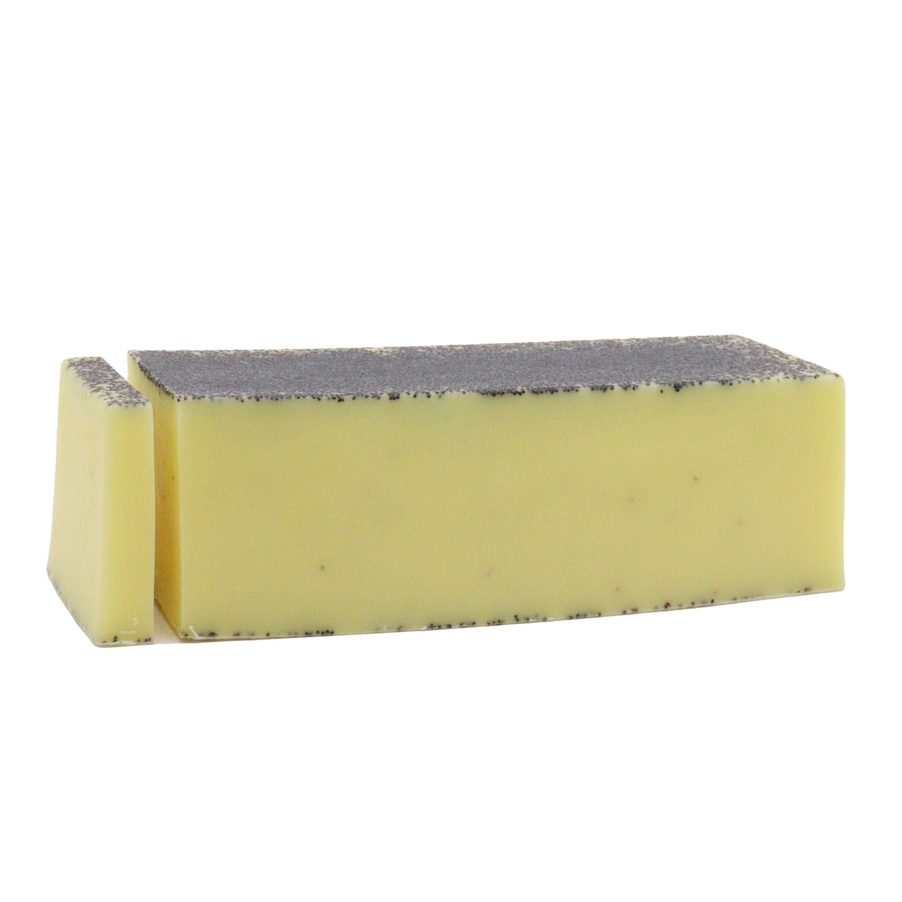 Textured yellow artisan soap loaf topped with poppy seeds and dried lemon slices on a rustic wooden surface.