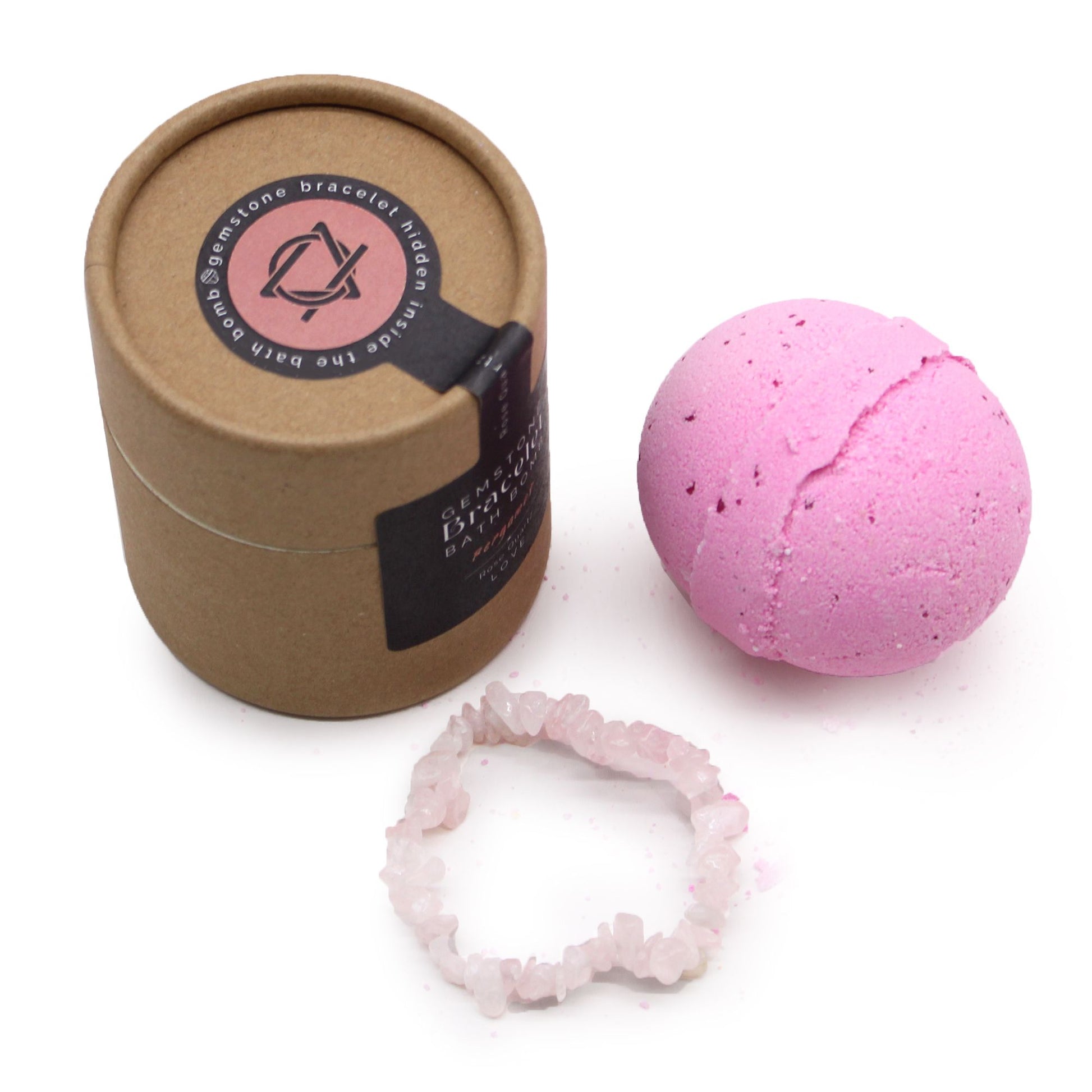 A round artisanal bath bomb with pink botanicals, containing a hidden rose quartz gemstone bracelet inside.