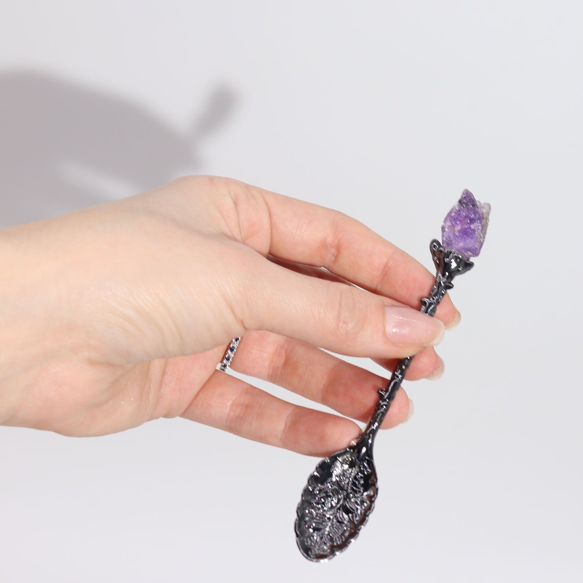 Set of seven dark silver decorative spoons each featuring a unique colourful gemstone crystal on the handle.