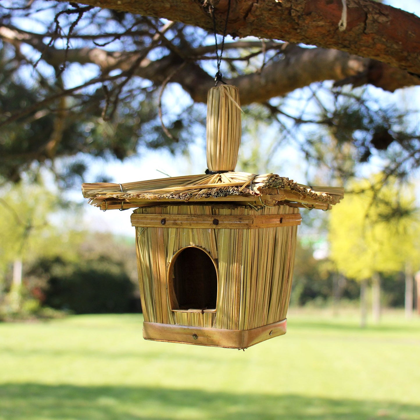 Small square bird house handcrafted from woven natural seagrass with a circular entrance hole.