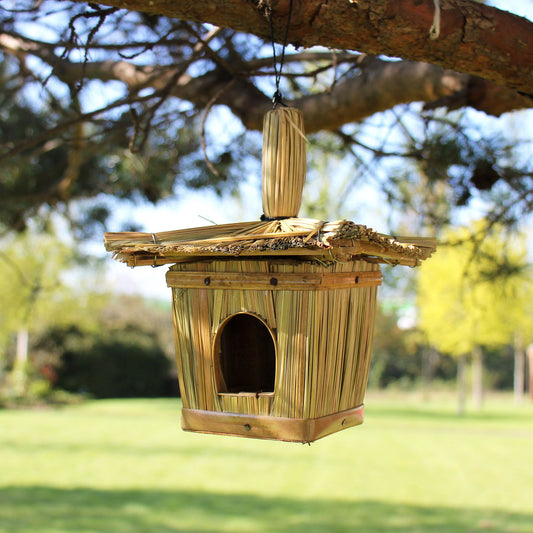 Small square bird house handcrafted from woven natural seagrass with a circular entrance hole.