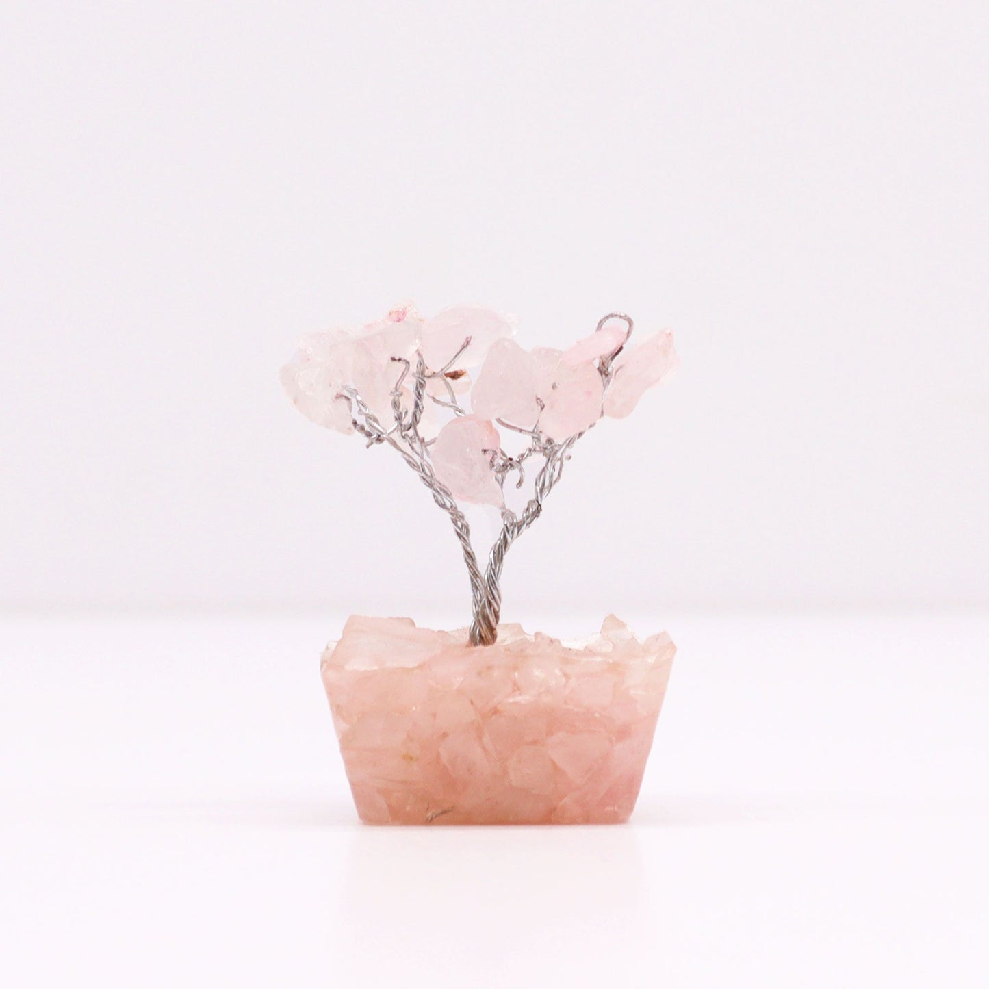 Delicate mini rose quartz gemstone tree with fifteen stones set on a decorative orgonite base.