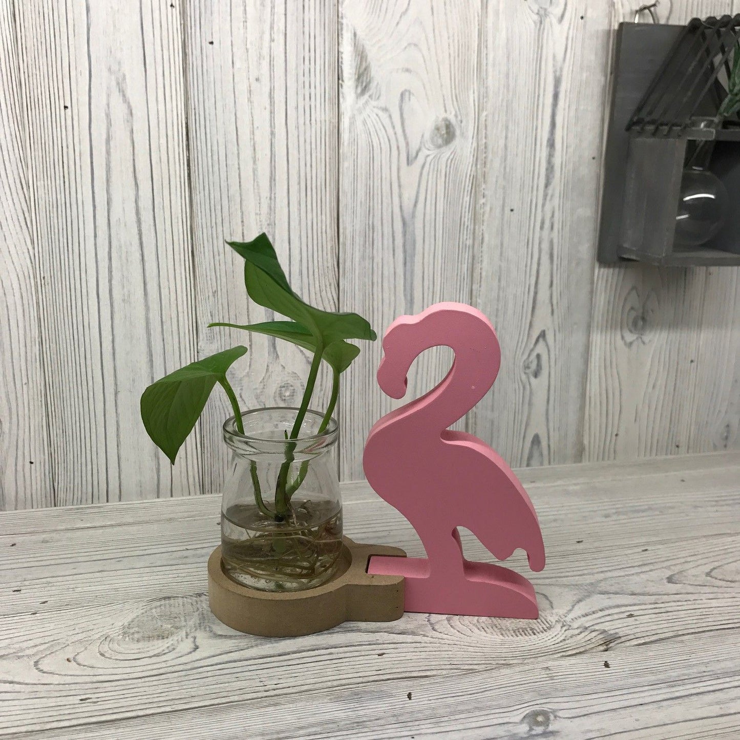 Stylish pink flamingo indoor planter with a glass propagation tube for hydroponic plants and flowers.