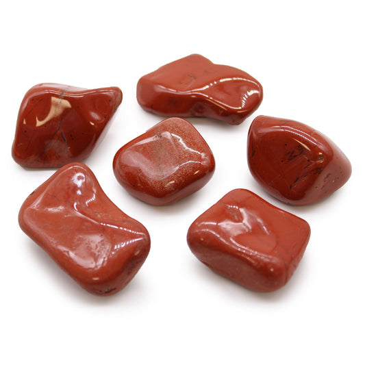 A collection of smooth, polished large red jasper tumble stones with deep terracotta and brick red hues.