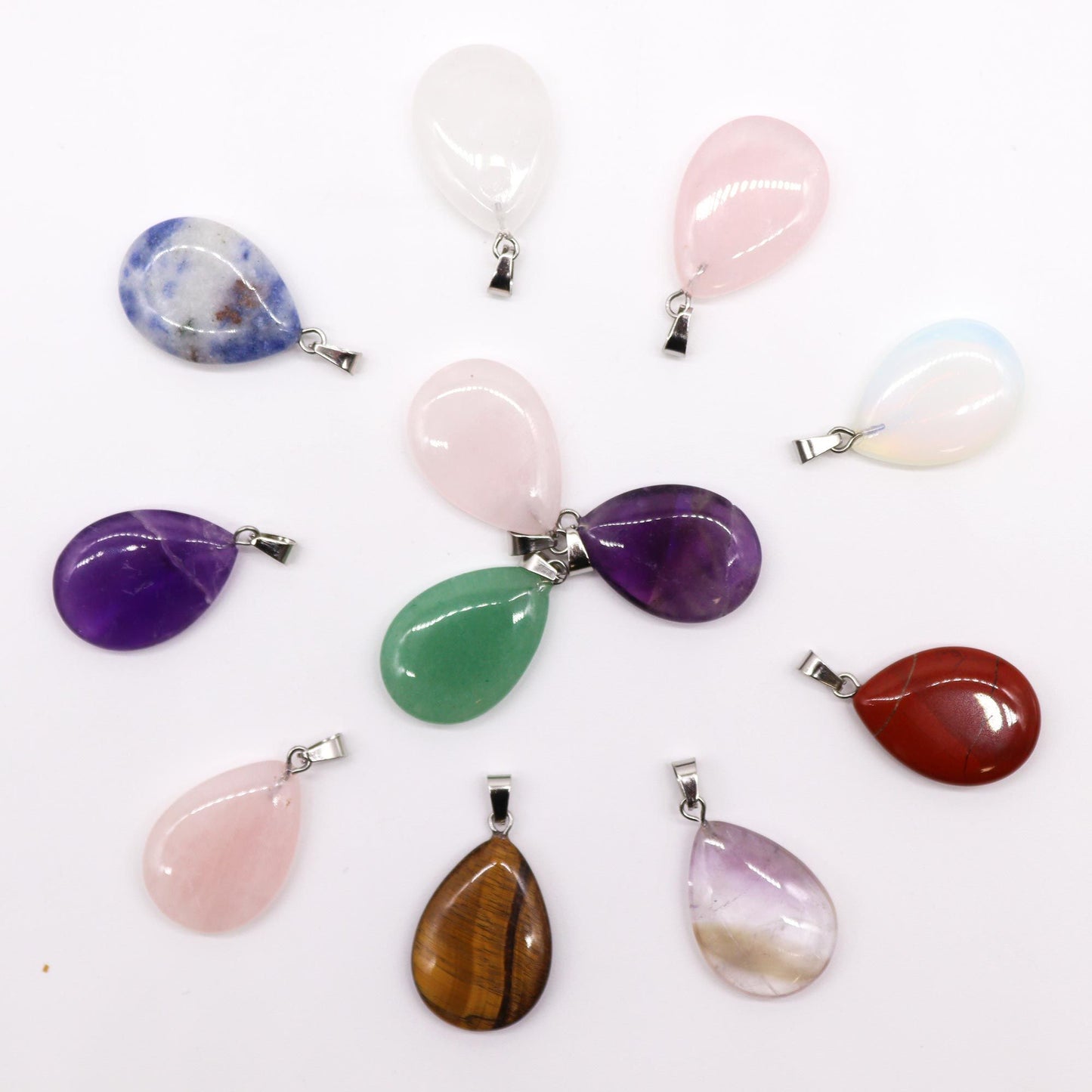 A collection of twelve polished gemstone pendants in various colours, each shaped into a smooth teardrop design.