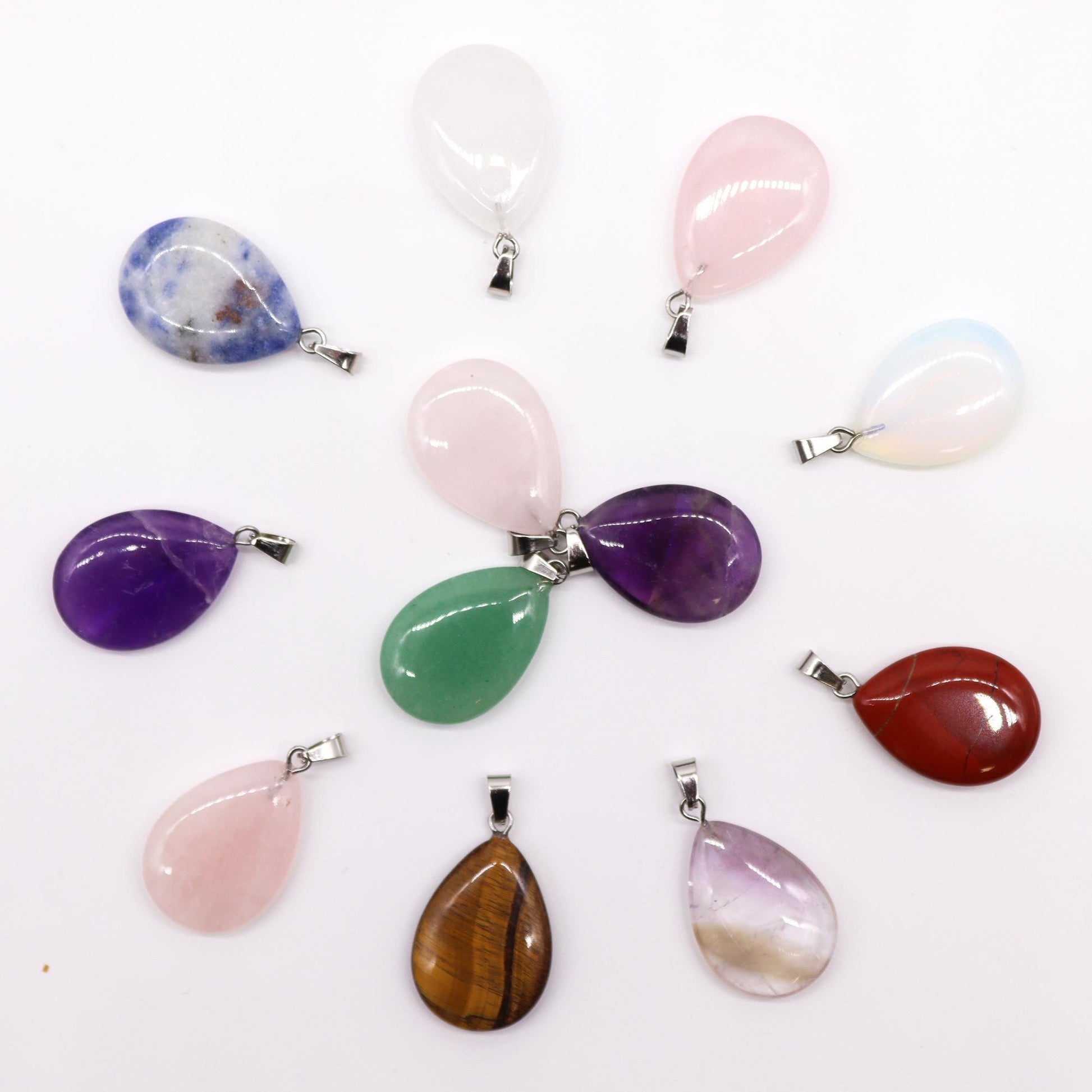 A collection of twelve polished gemstone pendants in various colours, each shaped into a smooth teardrop design.