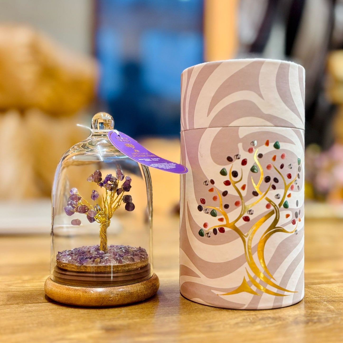 Handcrafted Amethyst gemstone tree with purple chipstones enclosed in a clear glass dome on a wooden base.