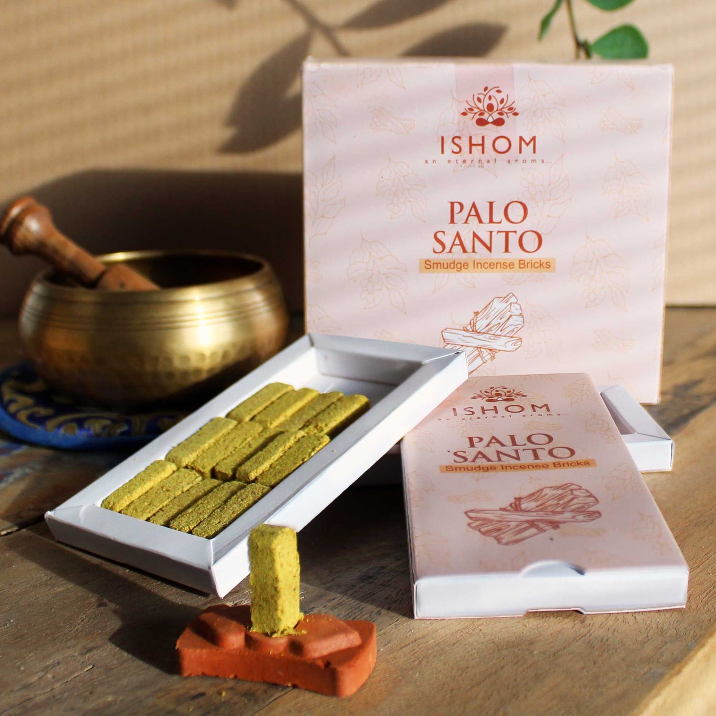 Set of fifteen rectangular natural Palo Santo incense smudge bricks beside a round carved terracotta burner holder.