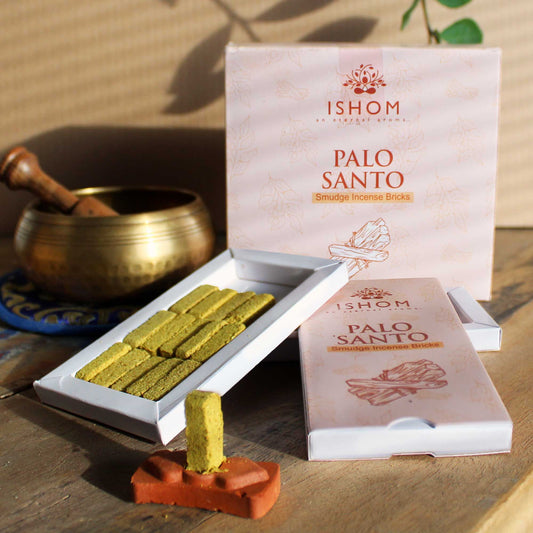 Set of fifteen rectangular natural Palo Santo incense smudge bricks beside a round carved terracotta burner holder.
