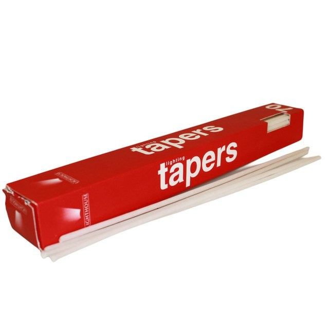 A collection of slim white wax lighting tapers neatly arranged in a cardboard box for ritual use.