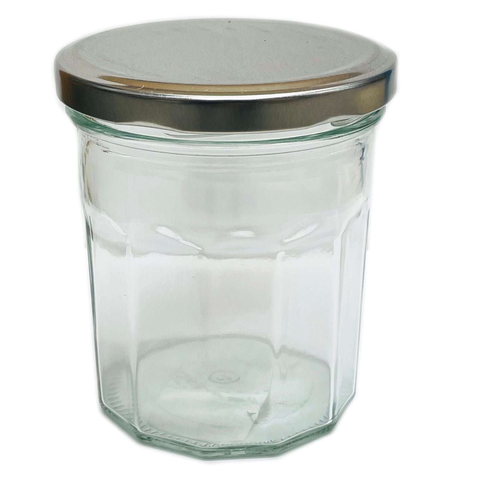 Clear twelve-sided faceted glass jam jar with a matching metal lid on a plain background.