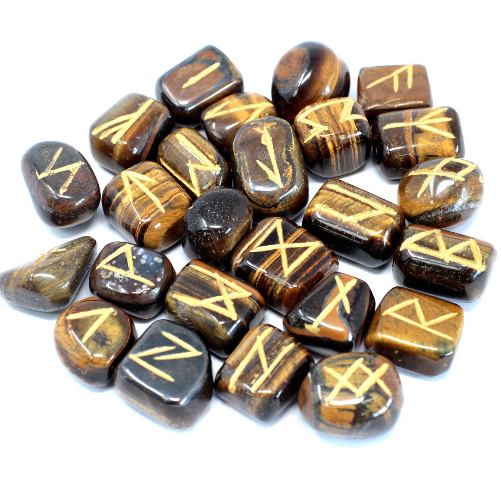 Golden brown Tiger Eye stones engraved with traditional rune symbols laid out next to a black drawstring pouch.