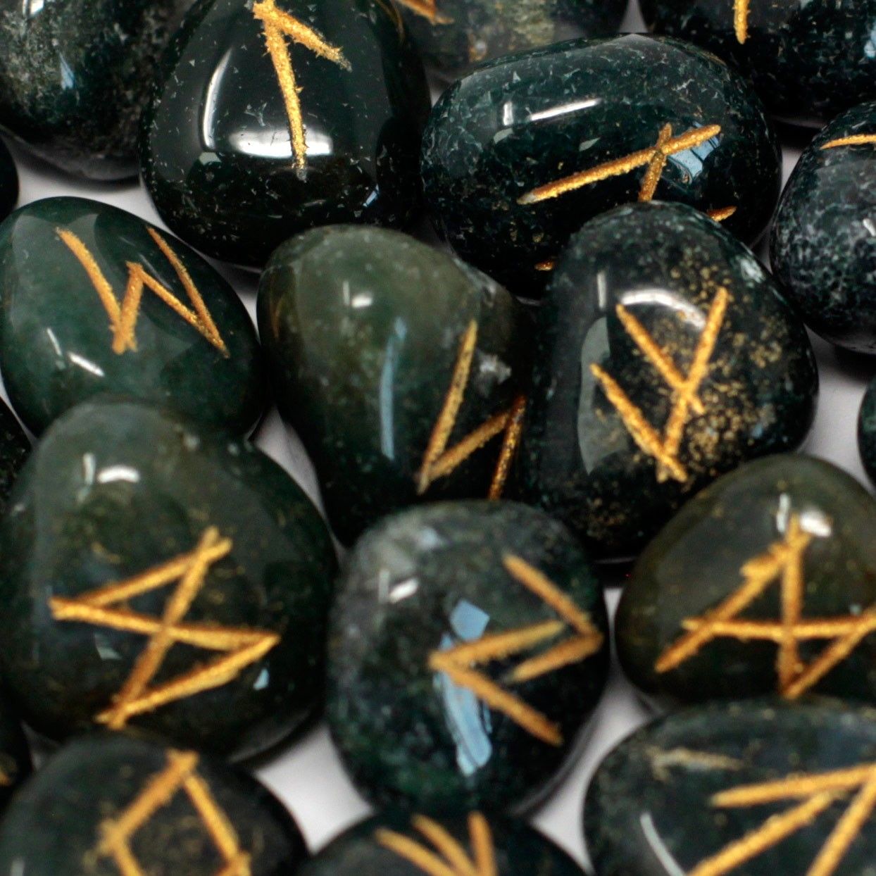 Polished dark green bloodstone rune stones with engraved gold lettering, presented in a small drawstring pouch.