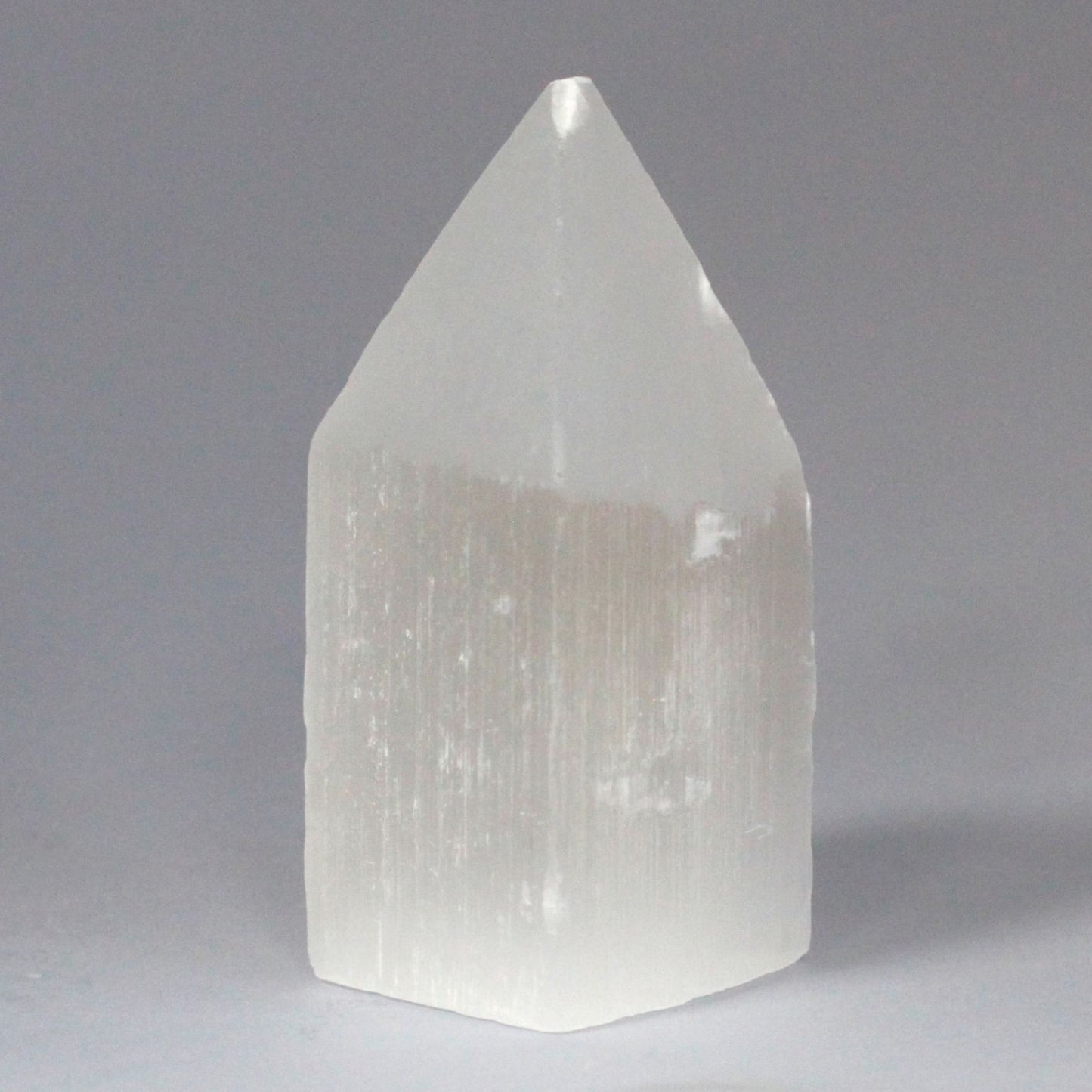 Tall white Selenite pencil point tower with a milky crystalline structure and translucent finish.