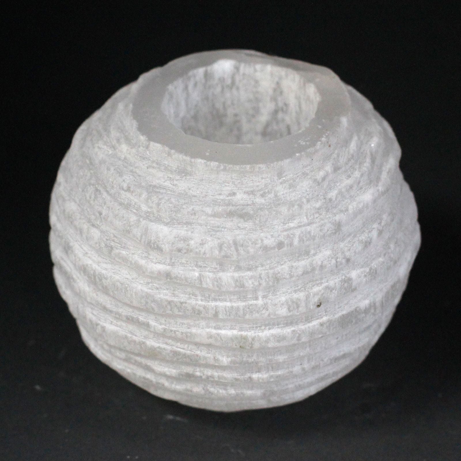 Round white selenite candle holder with a rough natural texture and a hollow centre for a tea light candle.