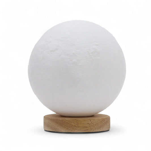 Textured spherical moon lamp on a wooden base emitting a soft warm glow in a dark room.