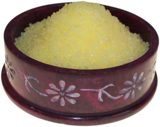 Pile of vibrant yellow citronella simmering granules for use in a home fragrance oil burner.