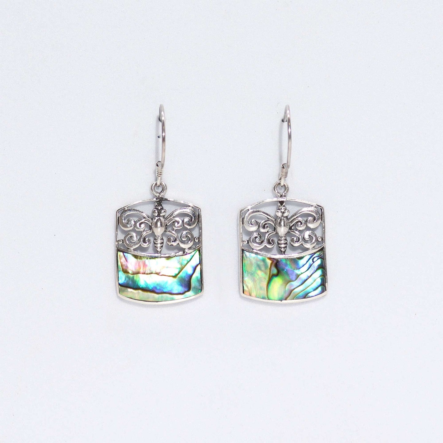 Detailed silver dragonfly earrings featuring iridescent abalone shell wings on a clean background.