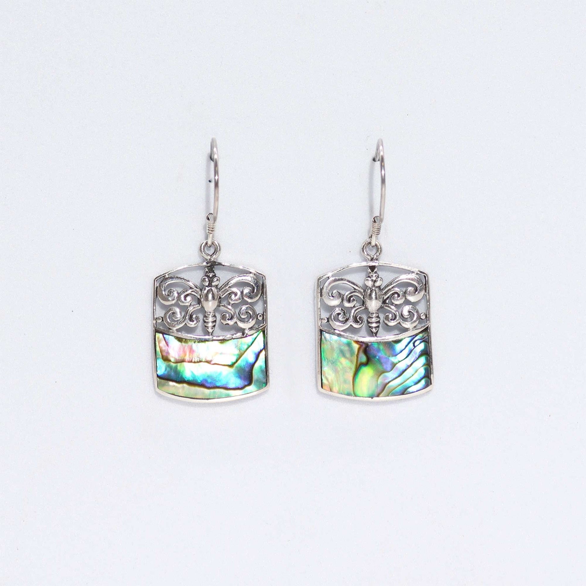Detailed silver dragonfly earrings featuring iridescent abalone shell wings on a clean background.