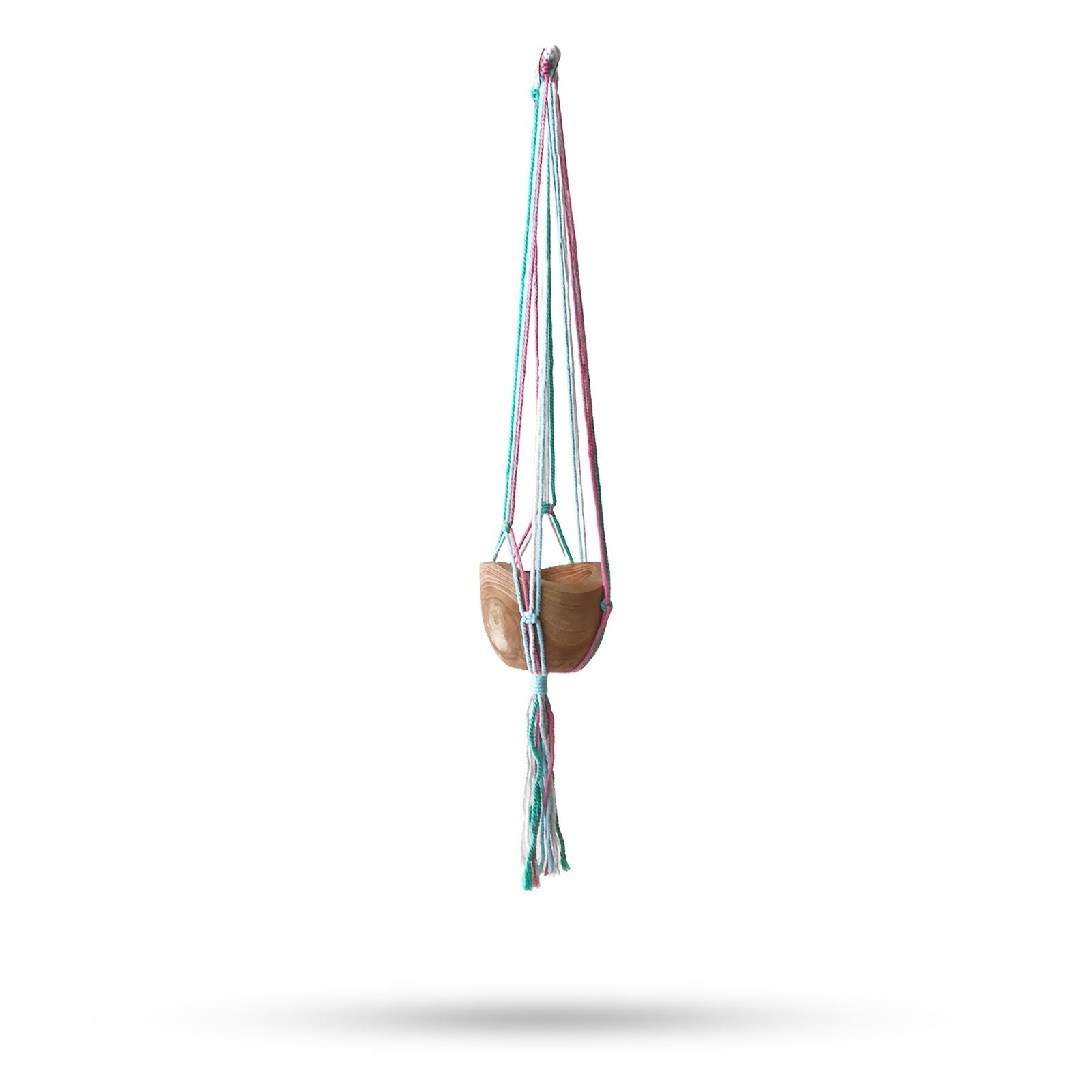 Hand-woven macrame plant hanger in soft pastel cotton with a medium-sized ceramic pot on a terrace.