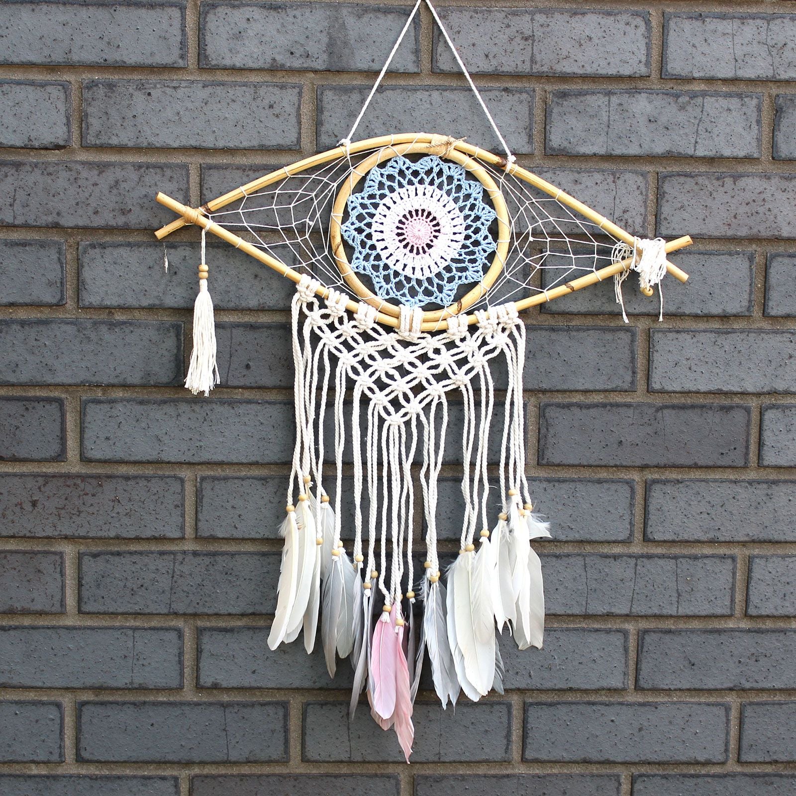 Medium macrame dream catcher with a blue and white evil eye motif, woven thread, and decorative tassels.