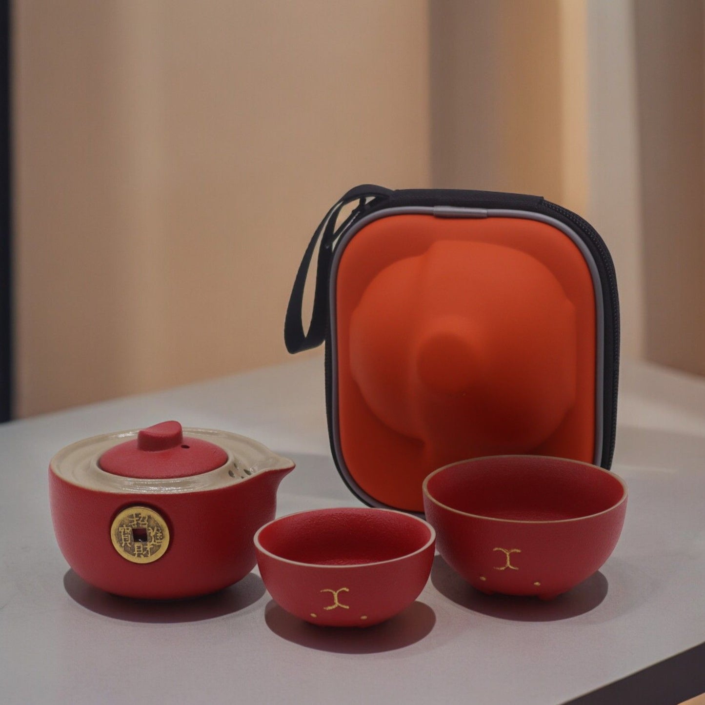 Adorable red ceramic teapot with a golden lucky cat design and two matching cups in a compact travel case.