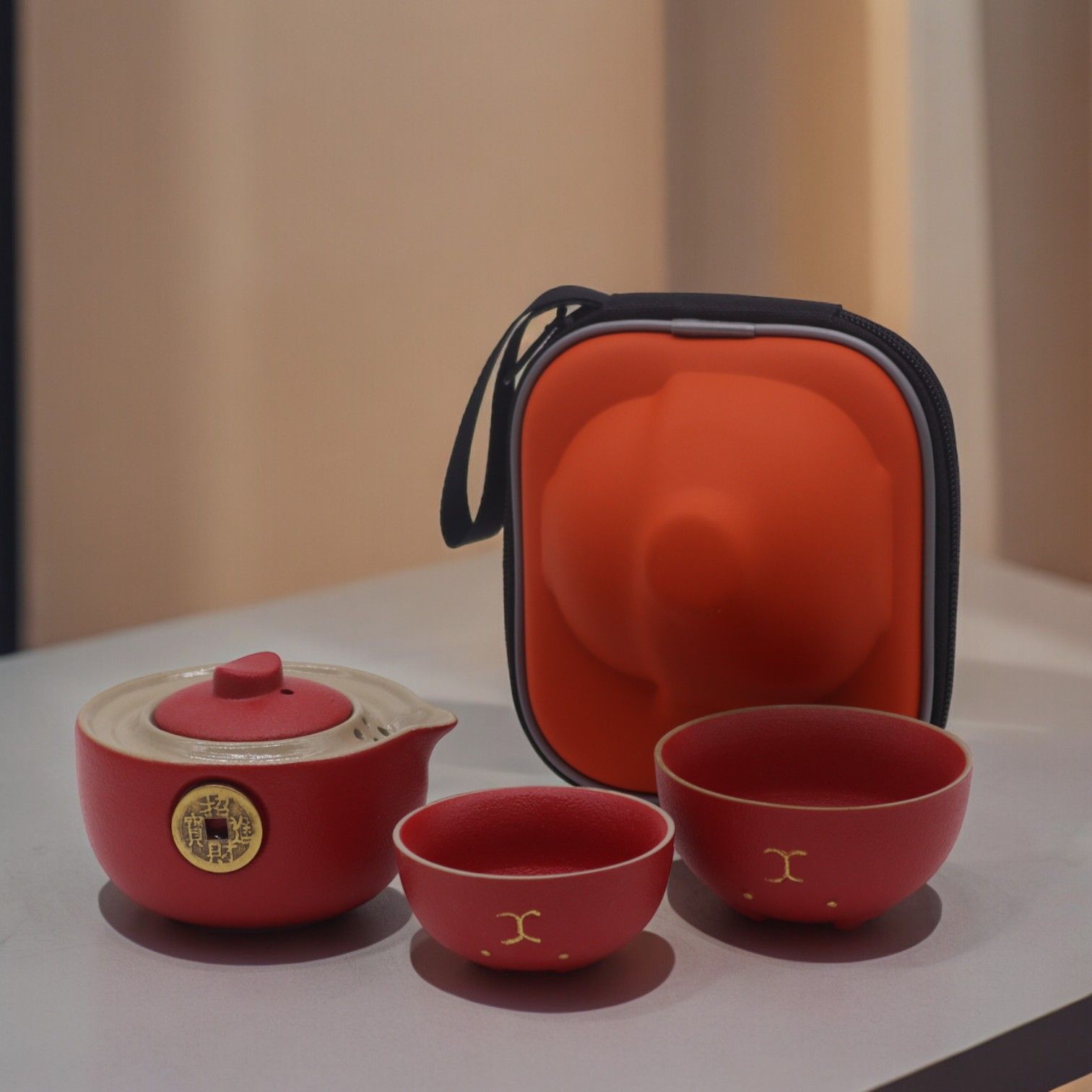 Adorable red ceramic teapot with a golden lucky cat design and two matching cups in a compact travel case.